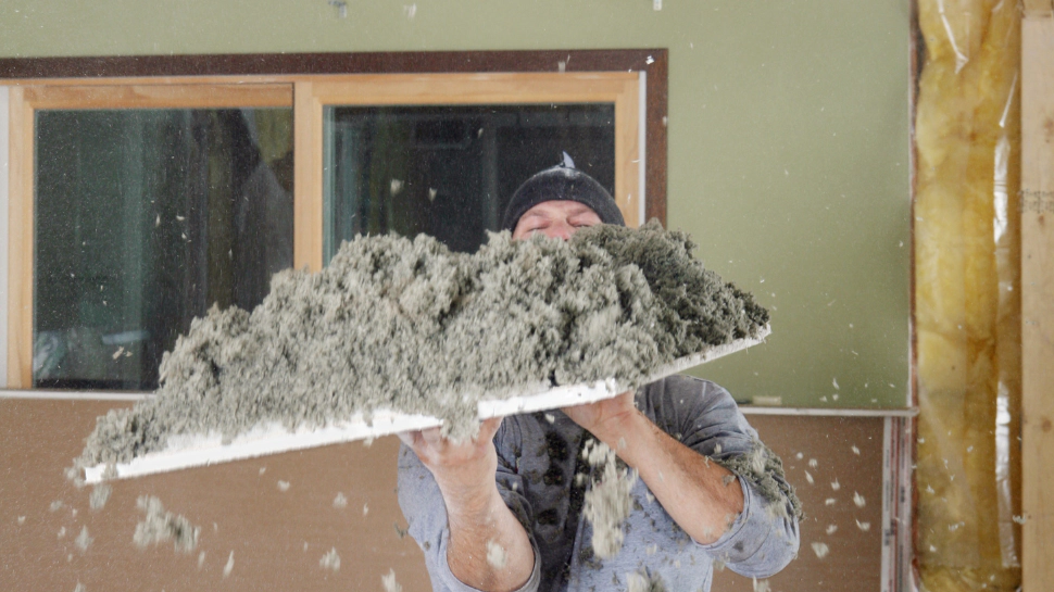 a person removing an old cellulose insulation